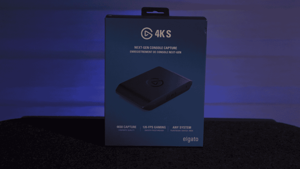 Fotografía de cerca de la capturadora Elgato 4K X junto a una laptop, mostrando lo pequeña y compacta que es en un escritorio ordenado